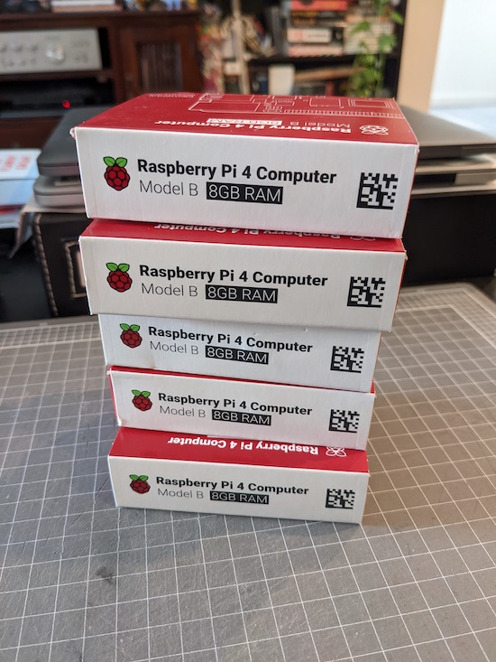 Five Raspberry Pi model 4B 8GB boxes stacked on top of each other, resting on an A3 cutting mat.