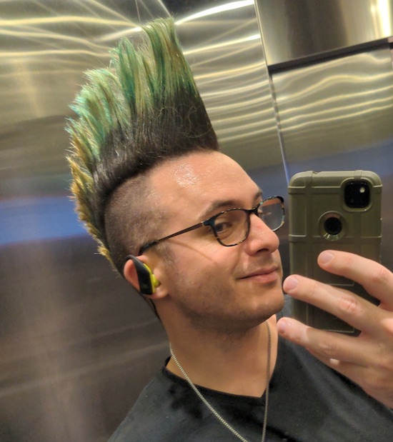An elevator mirror selfie of Az showing a partially front-on view of their mohawk looking tall and resplendent.